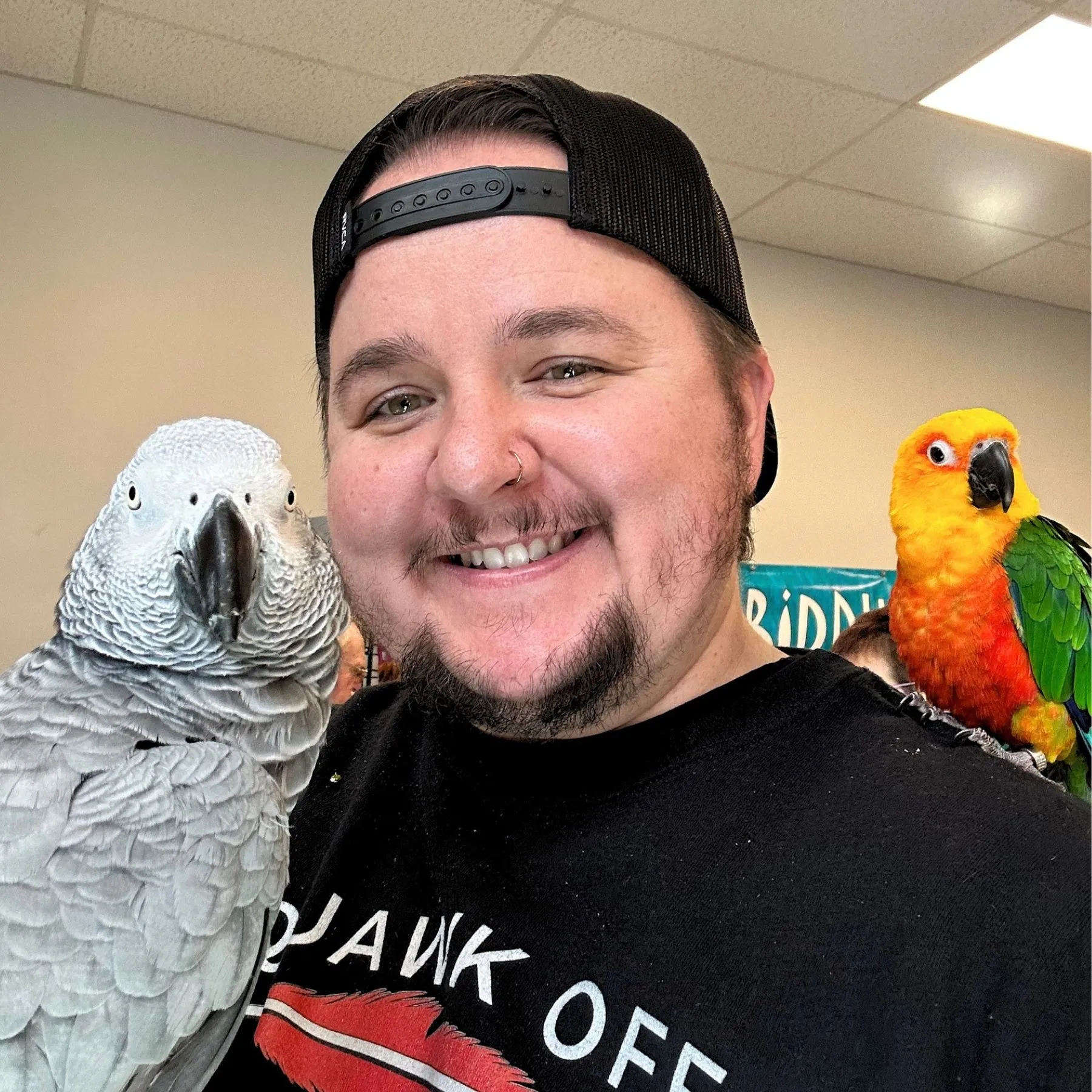 Kyle Kaplanis, Founder and CEO of Squawk Global, pictured with Gizmo the Grey Bird and a Jenday Conure. Kyle leverages nearly a decade of social media expertise and a network reach of over 1 billion followers to lead parrot advocacy.